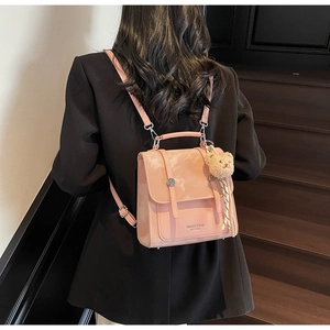 Dettaglio zaino in pelle rosa chiaro con ciondolo orsetto su modella in abito nero