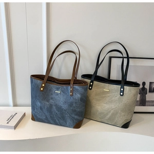 Detail of metal rivets and reinforced corners on minimalist tote bags in blue and beige