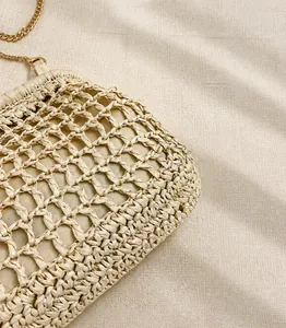 Detailed macro view of the cream woven mesh texture and gold chain on the casual beach bag