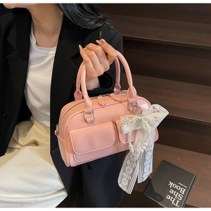 Pink Boston bag with white lace bow and pearl pendant details on a leather texture