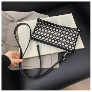 Detail of silver rivets on black leather handbag resting on a fashion magazine