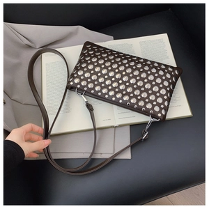 Detail of dark brown leather handbag with silver stud rivets and metal hook strap