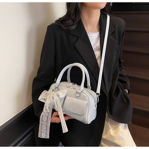 Close-up of light blue patent leather Boston bag featuring a lace pearl bow charm