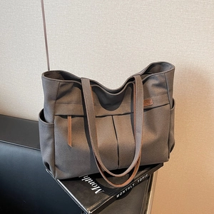 Large dark grey canvas tote bag with brown trim on leather sofa for daily commute