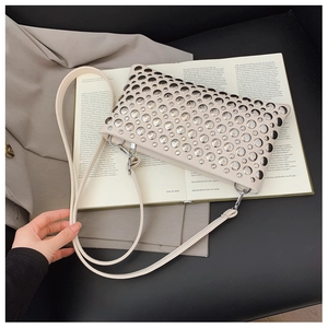 Detail of off-white rectangle bag featuring silver metal studs and leather strap
