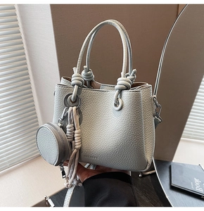 Detail of light blue lychee pattern leather handbag with knot handle and tassel charm