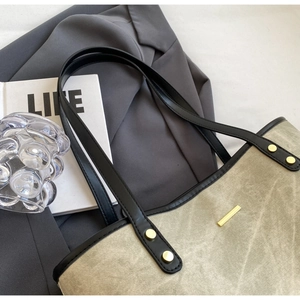 Detail of canvas tote bag with black leather handles and gold rivet accents