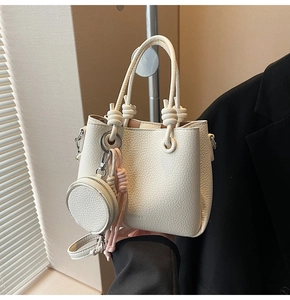 Close-up of white lychee texture bucket bag with pink tassel and mini round pouch