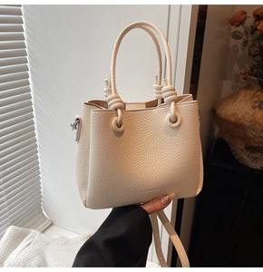 Detail of cream white bucket bag featuring lychee grain leather and knotted handle design