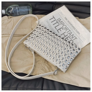 Detail shot of white crossbody bag with silver metal rivets and leather shoulder strap