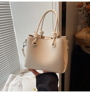 Close-up of white lychee texture leather bucket bag with elegant knot handle detail
