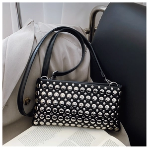 Detail of black punk shoulder bag featuring polished silver studs on leather surface