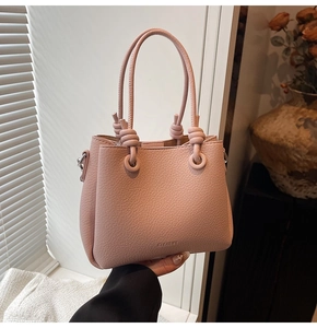 Close-up of pink bucket bag featuring litchi grain leather texture and knot detail