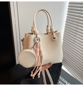 Detail of cream white leather bucket bag with mini coin purse and woven pendant detail