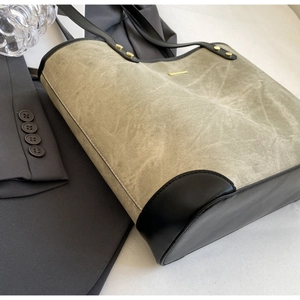 Detail of olive green tote bag with black leather patchwork and gold metal rivets