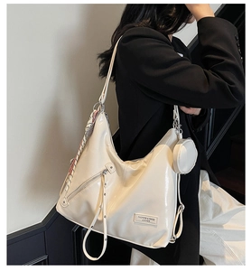 Macro view of cream-white leather tote featuring side drawstrings and round coin pouch