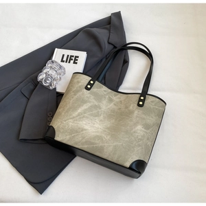 Close-up of khaki tote bag with nubuck texture and black leather accents in a lifestyle setting