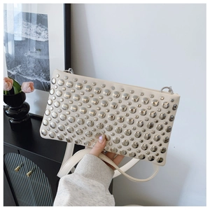 Close-up of cream rectangular bag with silver studs and detachable shoulder strap detail