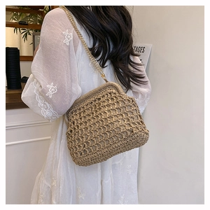 Detail of hand-woven straw crossbody bag with golden chain strap on a summer dress