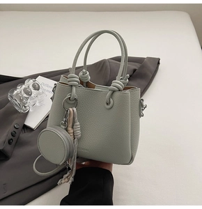 Detail of mint green bucket bag with knotted handles and matching round coin purse charm