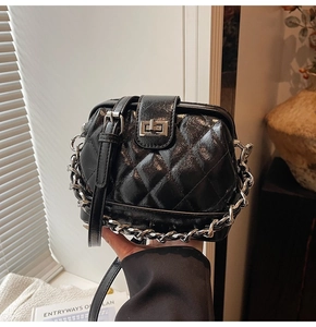 Dettaglio borsa a mano nera trapuntata con finitura vintage lucida e catena d'argento