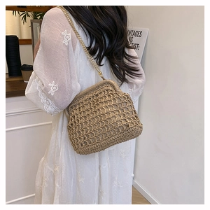 Close-up of khaki woven straw shoulder bag featuring gold chain and openwork texture