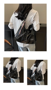 Detail view of glossy black hobo bag with braided charm and removable coin purse