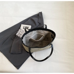 Detail view of khaki tote bag with black leather trim and internal zipper pocket