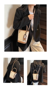 Détail d'un sac seau bicolore minimaliste avec bandoulière et pendentif décoratif