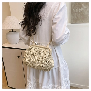 Detail of hand-woven beige clutch with golden chain strap on model in elegant setting