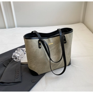 Detail of gray-green tote bag with black leather trim and elegant gold metal buckle