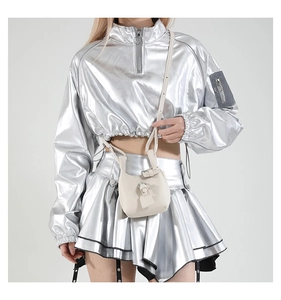 Detailaufnahme der cremefarbenen Umhängetasche mit silberner Schnalle und Metallik-Jacke