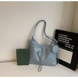 Détail d'un sac cabas bleu clair brillant avec fermeture éclair latérale et mini pochette
