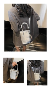 Détail d'un sac seau argenté montrant la texture métallique et le charmant pendentif ours