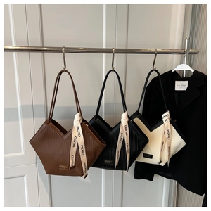 Detailed view of large vertical pleated tote bags in brown, black, and beige colors