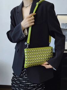 Grass green PU leather shoulder bag with silver rivet studs worn by model in black suit