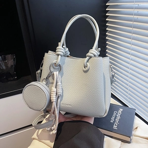 Minimalist light blue bucket bag with knot handle and round coin purse in natural lighting
