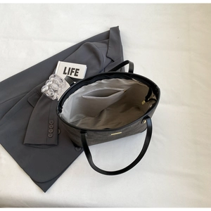 Interior view of grey tote bag with zipper pocket on a stylish suit and magazine