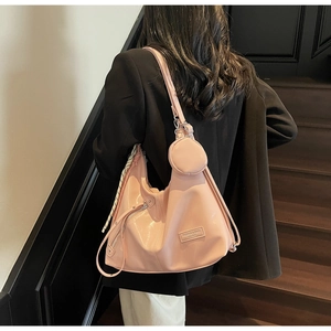 Détail du sac à main en cuir verni rose clair avec foulard rayé et accessoire porte-monnaie