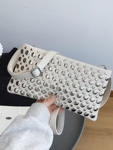 Chic cream leather handbag with silver metallic rivets and adjustable shoulder strap