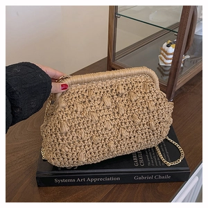 Detail of woven khaki straw clutch bag with gold chain strap on vintage background