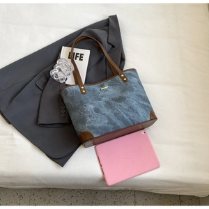Deep blue tote bag detail showing high-capacity design with brown leather trim and metal accent