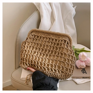 Detail of hand-woven straw cloud bag with golden metal chain on a soft chair