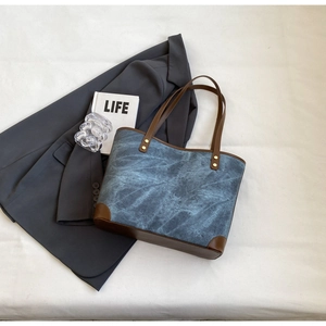 Detail of vintage blue canvas tote bag with brown leather accents and gold rivets
