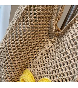 Detail of hand-woven mesh pattern with a yellow flower ornament on a beige tote bag