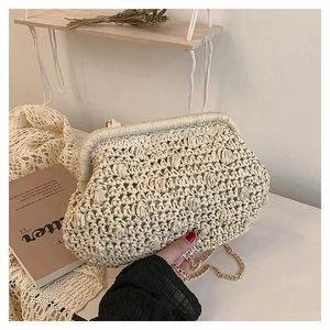 Detailed view of beige woven cloud bag with gold chain strap and textured straw finish