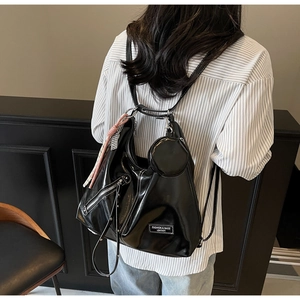 Détail du sac cabas noir brillant avec surpiqûres blanches et un petit porte-monnaie rond