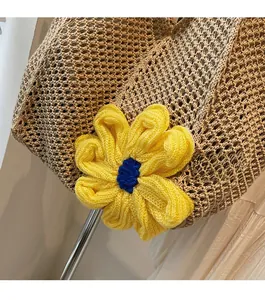 Detail of hollow woven tote bag featuring a large yellow and blue knit flower charm