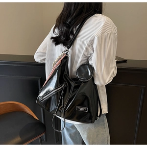 Détail du sac hobo noir verni avec patch logo mode et décoration en foulard de soie