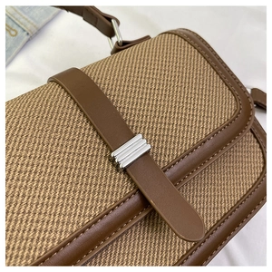 Detail of vintage flap bag showing brown leather trim and twill woven fabric texture
